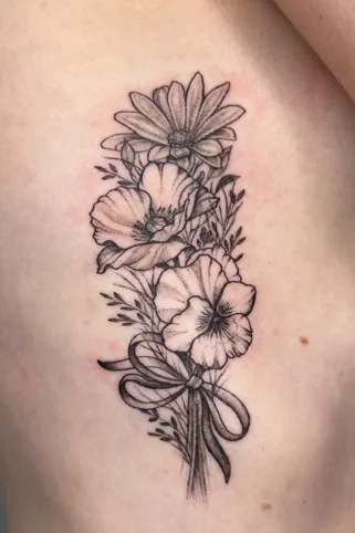 Fine line wildflower bouquet tattoo with ribbon detail